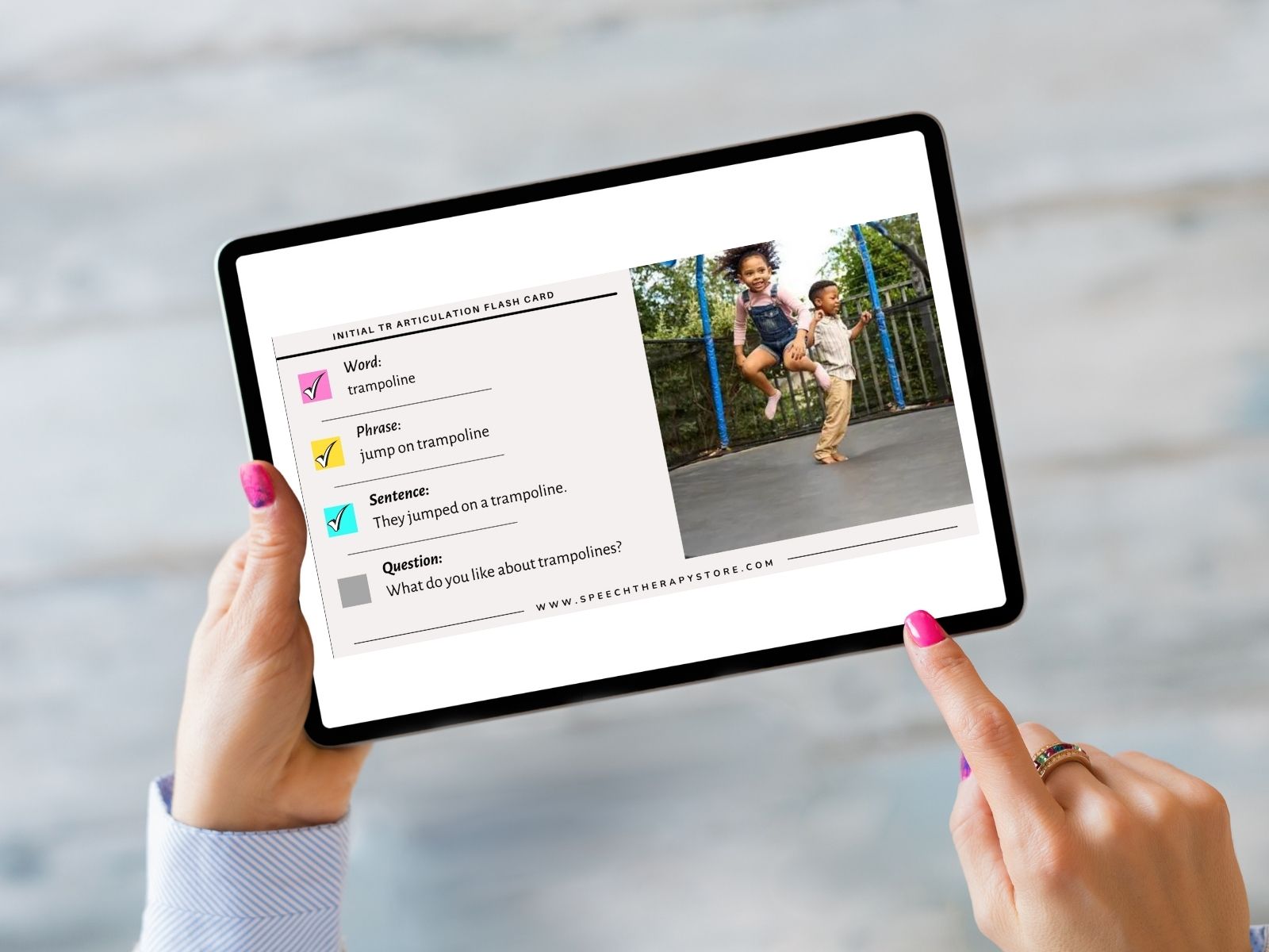 Tablet held in hands displaying a digital initial TR articulation flash card with word, phrase, sentence, and conversation question prompts.
