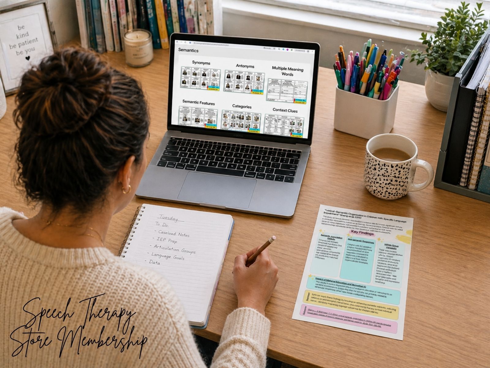 Speech-language pathologist working at a desk reviewing semantic language resources on a laptop with notes and therapy planning materials